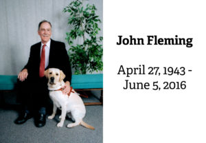 John Fleming seated next to his guide dog Tia. The caption says John Fleming, April 27, 1943 - June 5, 2016.