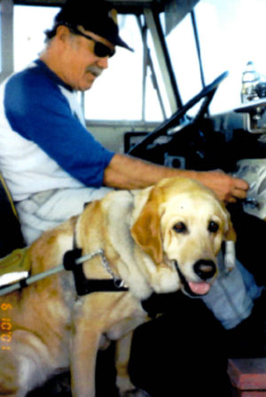 John behind the wheel of a van with Kiowa by his side